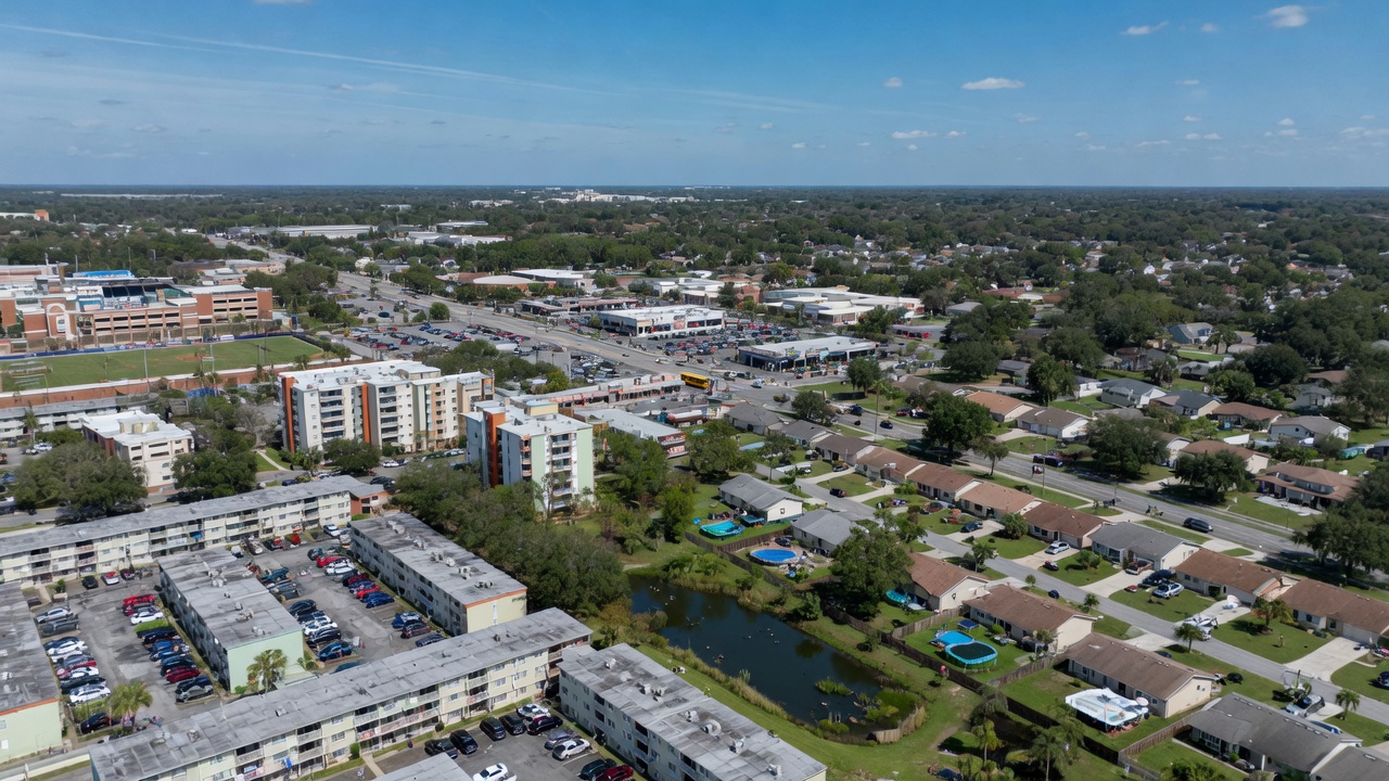 Ultra-realistic 8K aerial view of Gainesville Florida showing different neighborhoods from dense student housing near university to quiet suburban family areas, clear day with distinct zoning visible