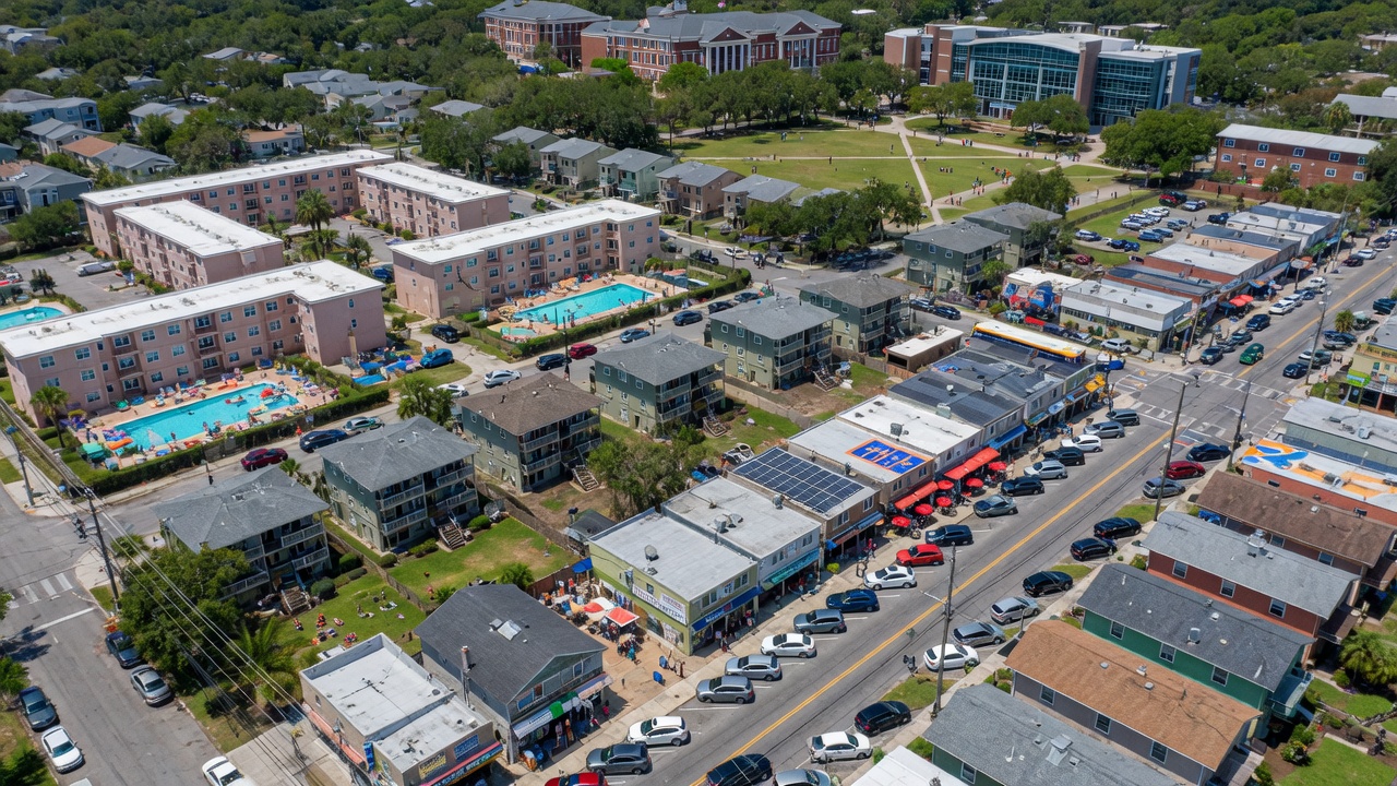 Ultra-realistic 8K aerial view of midtown Gainesville Florida neighborhood near University of Florida campus, mix of student housing and commercial buildings, clear day with excellent detail