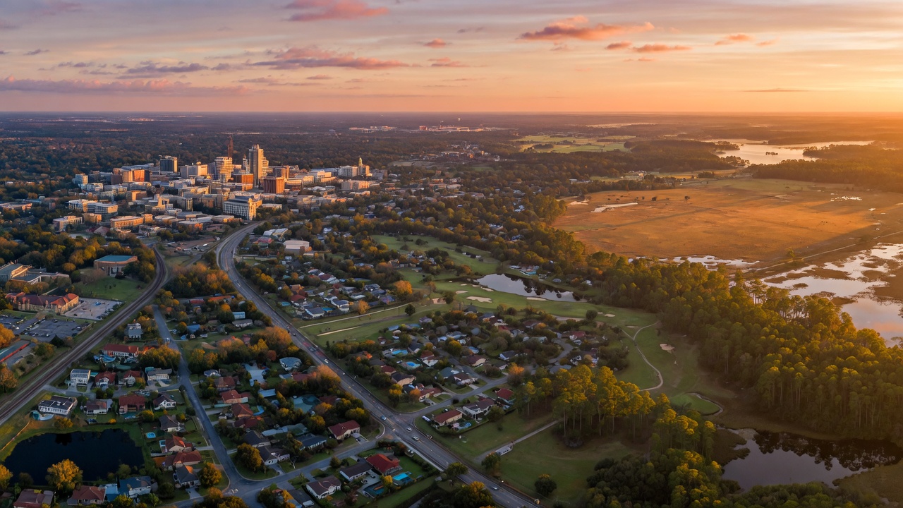 Epic 8K aerial photograph of greater Gainesville Florida region at sunrise showing mix of urban, suburban, and natural landscapes with golden light
